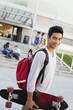 Student carrying skateboard outdoors