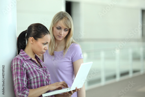 Photo: Two girls stood in the a corridor with a computer Two girls stood in the a corridor with a computer