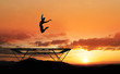 silhouette of female gymnast on trampoline in sunset