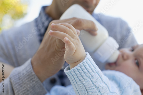 Photo: Father feeding baby from bottle Father feeding baby from bottle