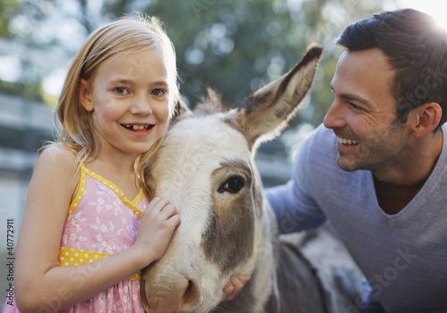 Foto: Father and daughter petting donkey Father and daughter petting donkey