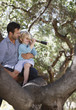Father and son playing with telescope in tree