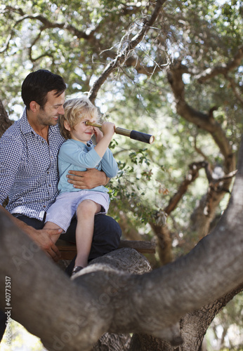 Photo: Father and son playing with telescope in tree Father and son playing with telescope in tree