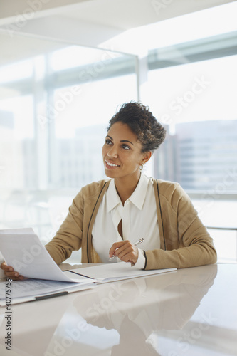 Photo: Businesswoman reading papers in office Businesswoman reading papers in office