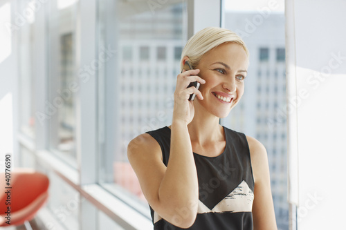 Photo: Businesswoman talking on cell phone in office Businesswoman talking on cell phone in office