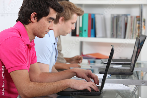 Photo: young male students in class working on laptops young male students in class working on laptops