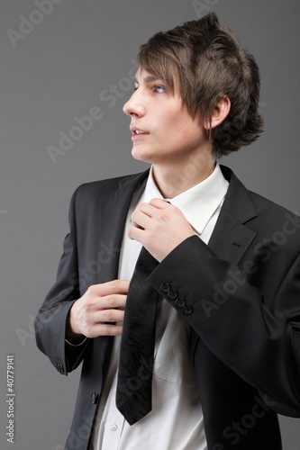 Photo: young businessman black suit casual tie on gray background young businessman black suit casual tie on gray background