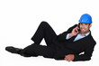 Architect laying on floor making telephone call