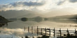 Fence in still lake in rural landscape