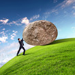 Businessman rolling a giant stone