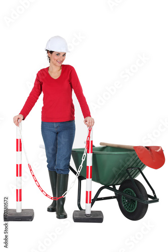 Photo: Woman worker with a wheelbarrow and barrier Woman worker with a wheelbarrow and barrier