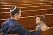 Father and son wearing yarmulkes in synagogue