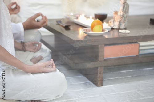 Photo: Couple meditating together in living room Couple meditating together in living room