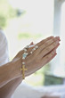Close up of clasped hands holding prayer beads