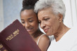 Older woman and granddaughter reading Bible together