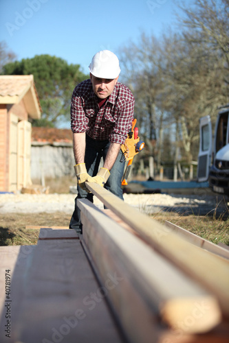 Foto: Carpenter arranging wooden beans on work-site Carpenter arranging wooden beans on work-site