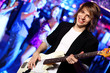 Young guitar player performing in night club