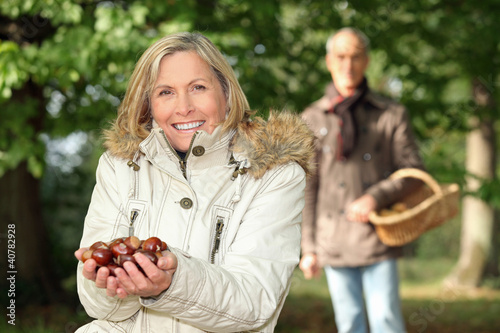 Photo: mature woman in woods with husband showing chestnuts mature woman in woods with husband showing chestnuts