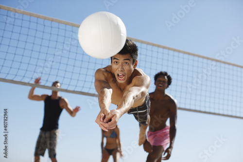 Photo: Man diving for volleyball on beach Man diving for volleyball on beach