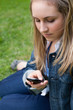 canvas print picture - Young girl sending a text while sitting on the grass