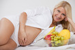 glückliche schwangere frau mit babybauch und obst