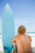 Foto: Blonde man sitting on the beach with his arms around his legs Blonde man sitting on the beach with his arms around his legs
