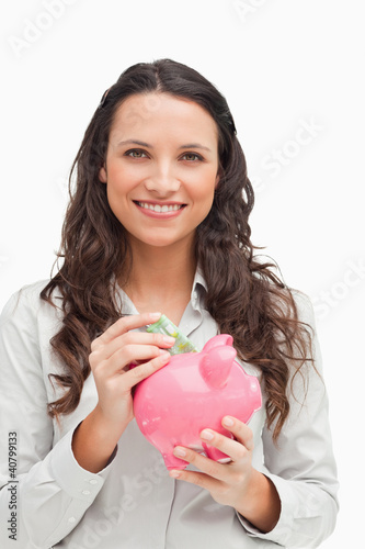 Photo: Brunette putting money in the piggy bank Brunette putting money in the piggy bank