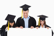 Three students having graduated holding blank sheet and looking