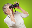 portrait of senior woman looking through a binoculars over green portrait of senior woman looking through a binoculars over green