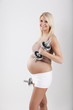 junge hübsche frau mit babybauch macht fitness mit hanteln