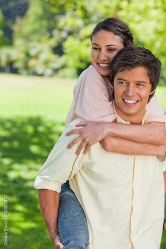 Photo: Woman holding her friend tight as he is carrying her on his back Woman holding her friend tight as he is carrying her on his back