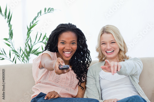 Foto: A woman pointing a television remote control at the camera with A woman pointing a television remote control at the camera with