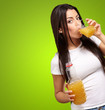 portrait of young girl drinking orange juice against a green bac portrait of young girl drinking orange juice against a green bac