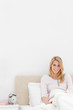 Vertical shot, Woman sitting up against headboard smiling with a