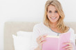 Woman holding her book in hand, while in bed looking forward and
