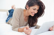 Woman using a tablet with her credit card, and smiling while lyi