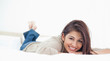 Low angle, woman lying on the bed, smiling with her legs crossed