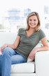 Close up, smiling woman with crossed legs sitting on couch