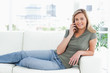 Woman lying across the couch, smiling, looking forward and makin