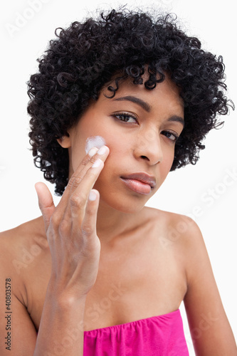 Photo: Young woman applying cream to her face Young woman applying cream to her face