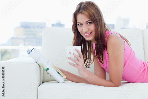 Photo: Young woman smiling while looking at the camera and holding a cu Young woman smiling while looking at the camera and holding a cu