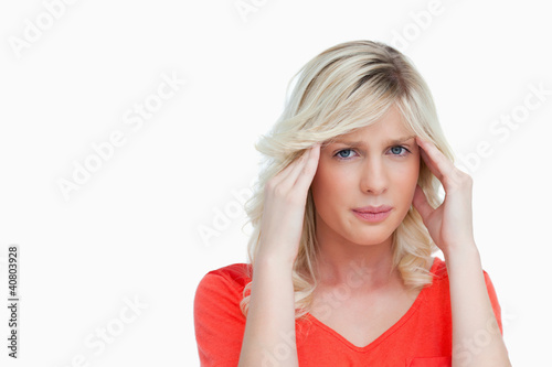 Photo: Young woman placing her hands on her temples while suffering fro Young woman placing her hands on her temples while suffering fro