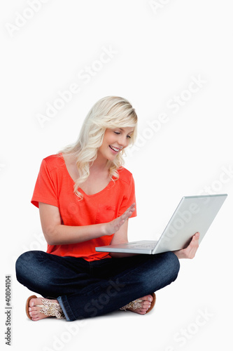 Photo: Fair-haired woman waving her right hand in front of her laptop s Fair-haired woman waving her right hand in front of her laptop s