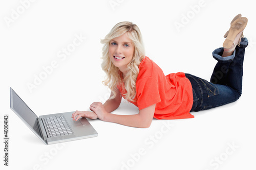 Photo: Smiling blonde woman crossing her legs in front of her laptop Smiling blonde woman crossing her legs in front of her laptop