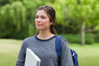 canvas print picture - Young smiling woman looking far away while standing in a park wi