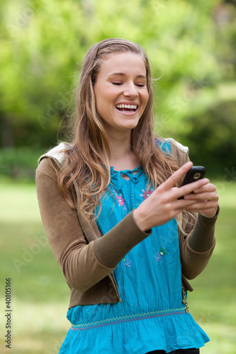 Photo: Teenage girl laughing while receiving a text on her cellphone Teenage girl laughing while receiving a text on her cellphone