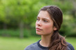 canvas print picture - Thoughtful young woman standing in a park while looking towards