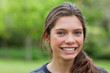 canvas print picture - Smiling young woman looking at the camera while standing in a pa