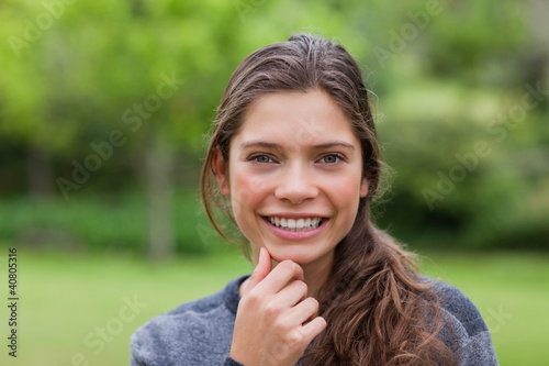 Photo: Smiling girl placing her hand on her chin while standing upright Smiling girl placing her hand on her chin while standing upright