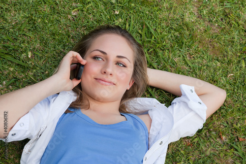 Photo: Young relaxed blonde girl lying on her back while talking on the Young relaxed blonde girl lying on her back while talking on the